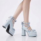 Light blue platform heels with ruffles worn with a white skirt on a white background